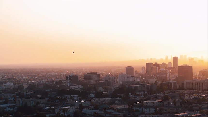 Aerial view of a helicopter flying over the skyline of the citys downtown at sunset