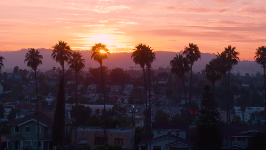 The sun is setting above a downtown city