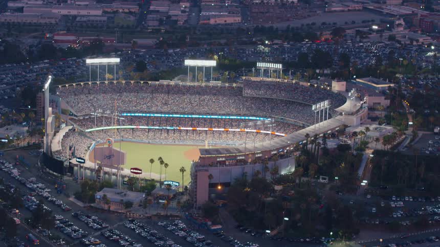 Lights shining on Dodger Stadium full of people waiting for a baseball game to start