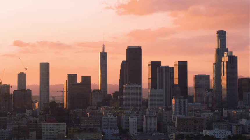 Aerial view of the downtown Los Angeles skyline at sunrise or sunset with light glinting off of the buildings