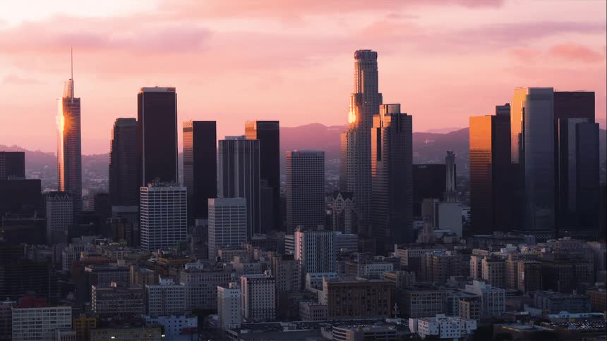 Aerial view of the tall skyscrapers of the downtown Los Angeles skyline reflecting the golden light at sunset