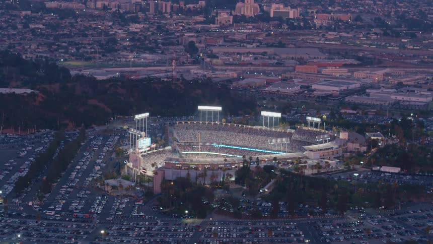 Crowded dodger stadium is lit up at sunset during a big game