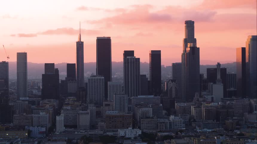 The rising sun turns the sky pink over a city skyline