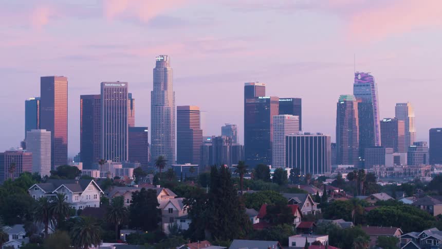 A view of a city against a blue and pink sky with neighborhoods on the outskirts