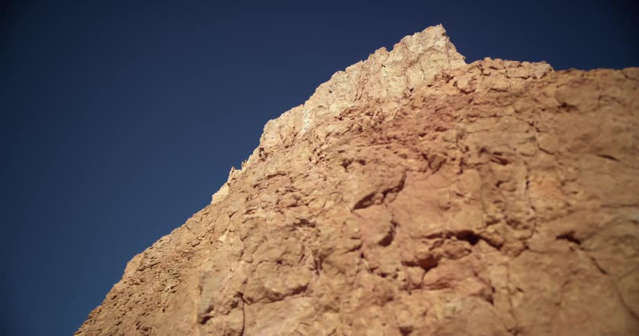 The peak of a golden hued canyon sits against a deep blue sky