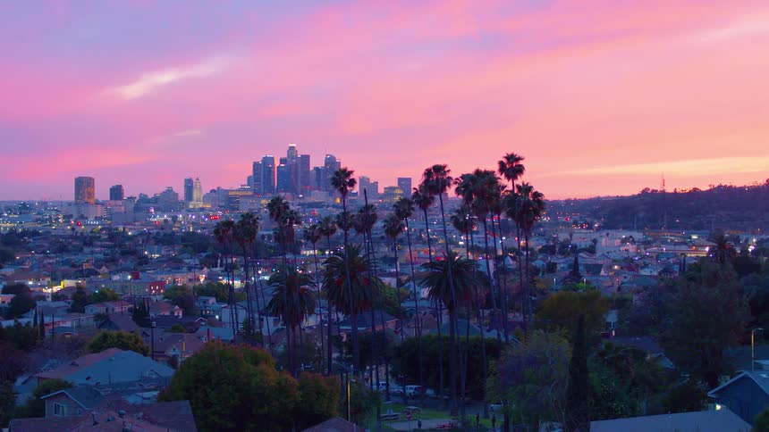 The sun is setting on a cloudy day by the city