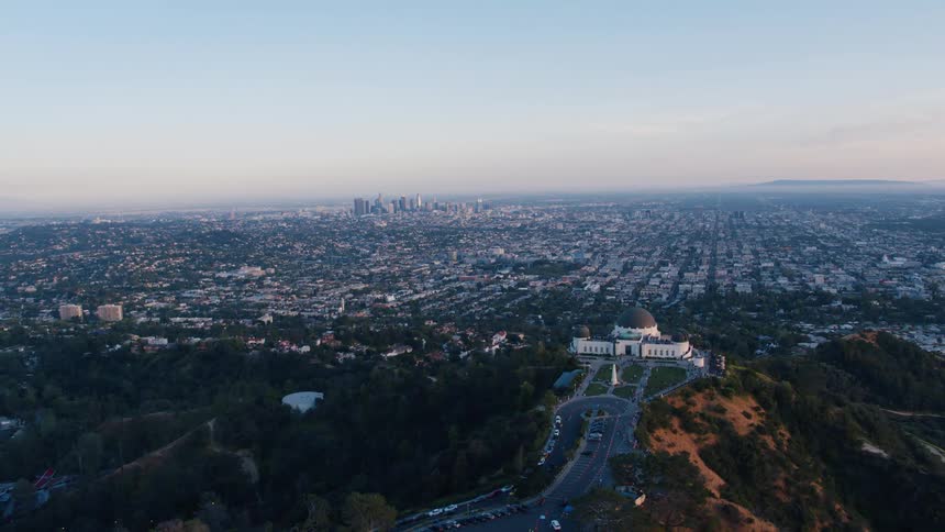 An aerial view of cars driving to a large building on a hill in city