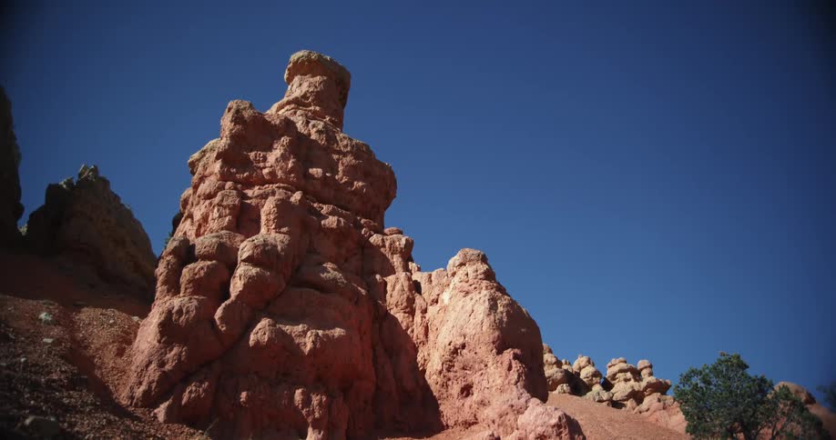 A formation of reddish stone on a slope under a clear blue daytime sky