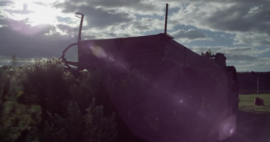 Sunlight shines through the clouds onto a wooden wagon resting in a field