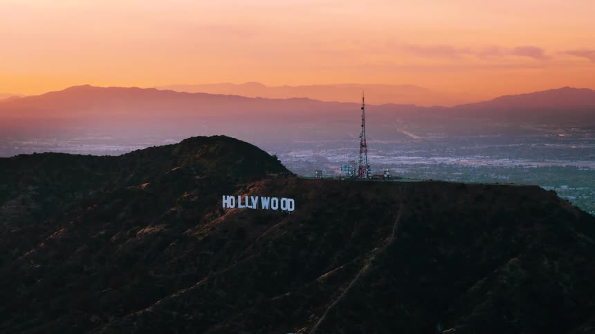 An electrical tower on a hill with the city skyline in the distance