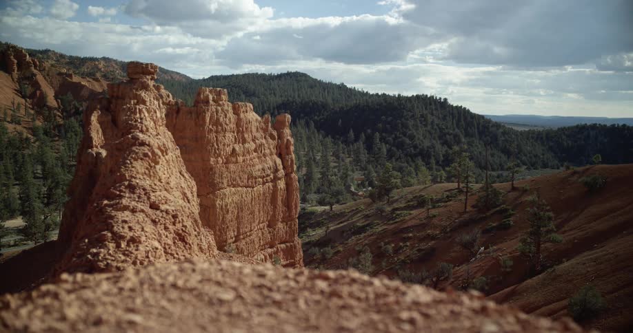 A rocky prominence sticks outwards in front of a mountain covered in a dense forest