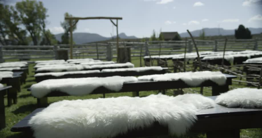 A corral is filled with tables with white pelts laid out in the sun