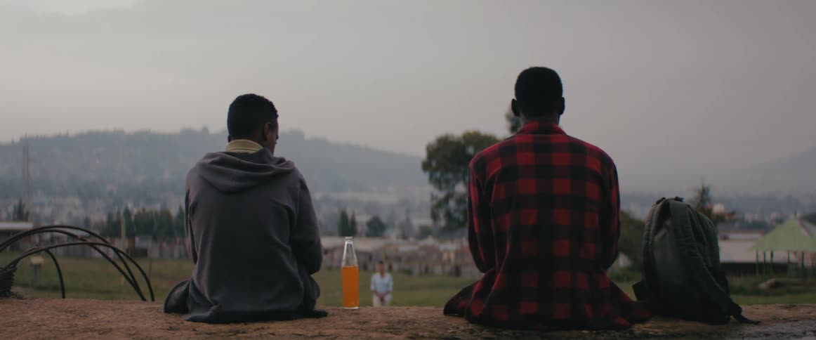 Two friends sitting outdoors sharing a soft drink at evening