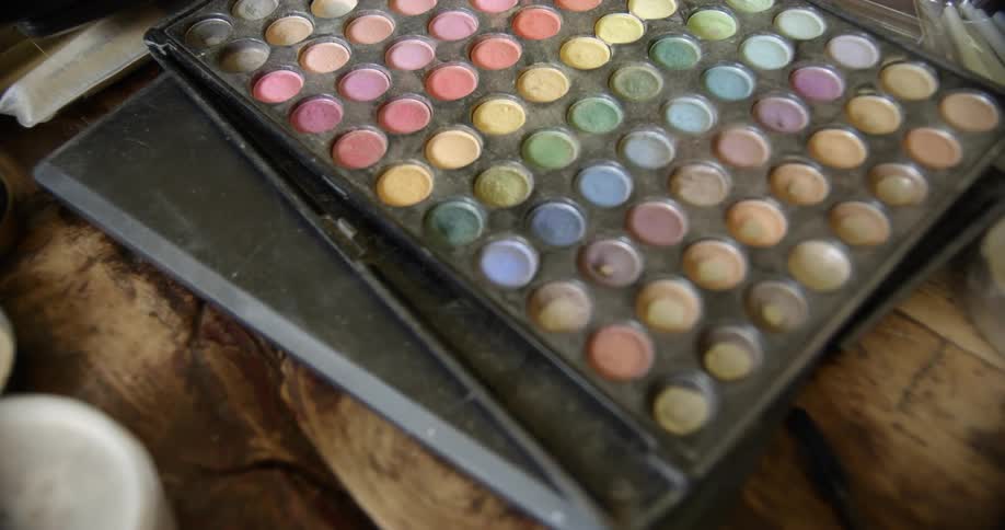 A close up of a palette of colorful eyeshadows sitting on a wood surface