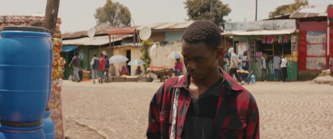 A young man standing along side the street looks on with uncertainty before walking away