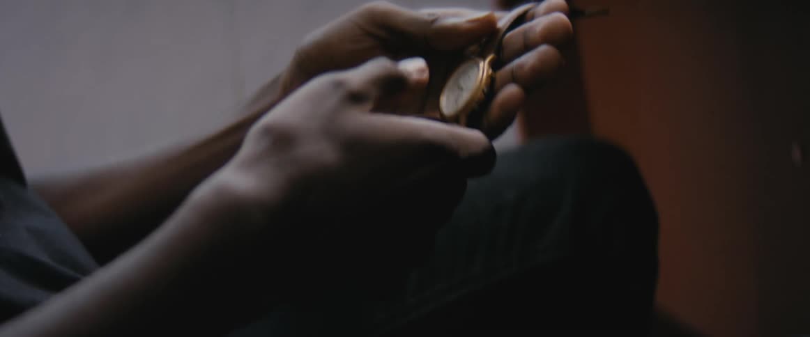 A person unbuckles the strap of a a wristwatch to hold it in the hands