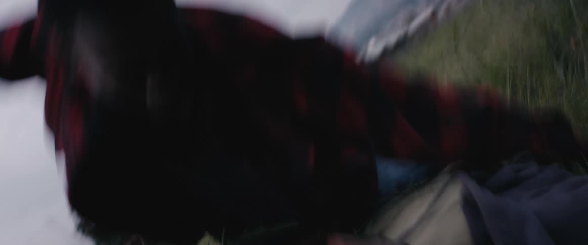 A man gets the upper hand on another man on top of him and punches him in the face as they lie in a field
