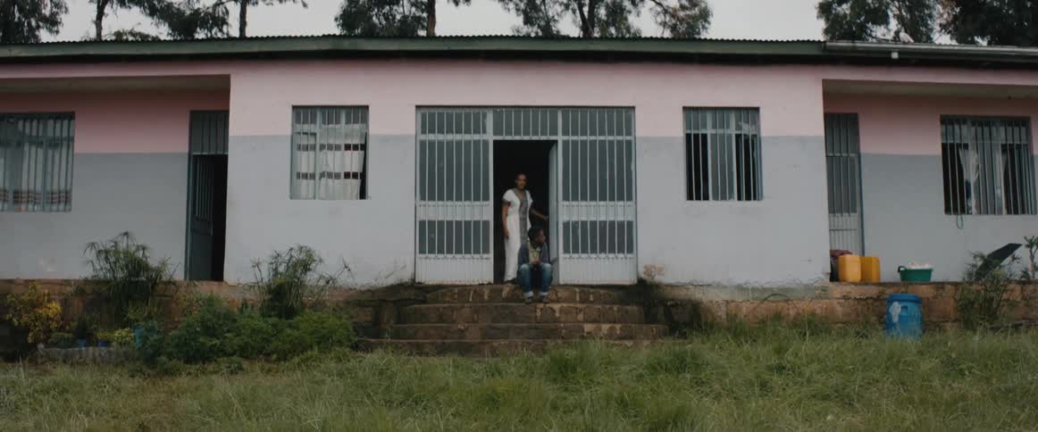 A teenager sitting on a porch when someone opens the door