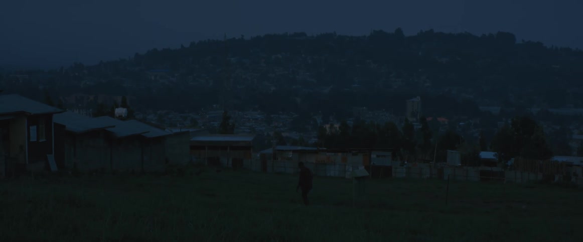 A person is walking over the field at sunset
