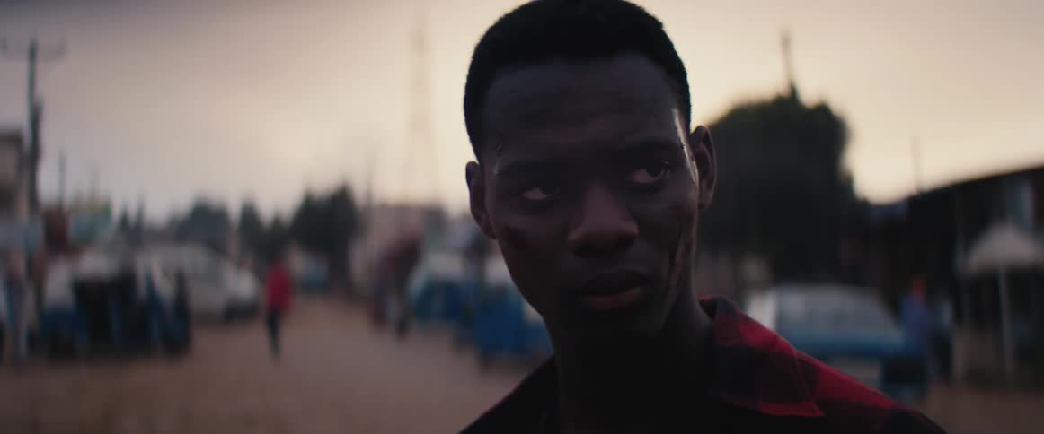 Close up of the face of a worried or sad teenager in the street of a small town at evening