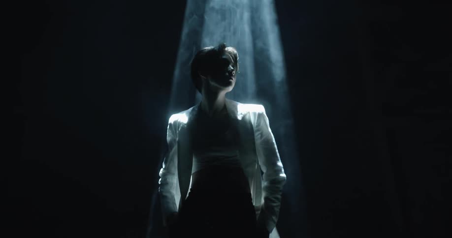 Young man standing in a dark smoky room standing under a spotlight