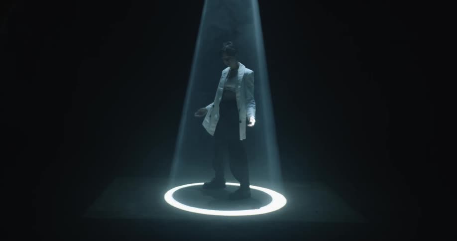 Woman standing under a projector inside a dark studio