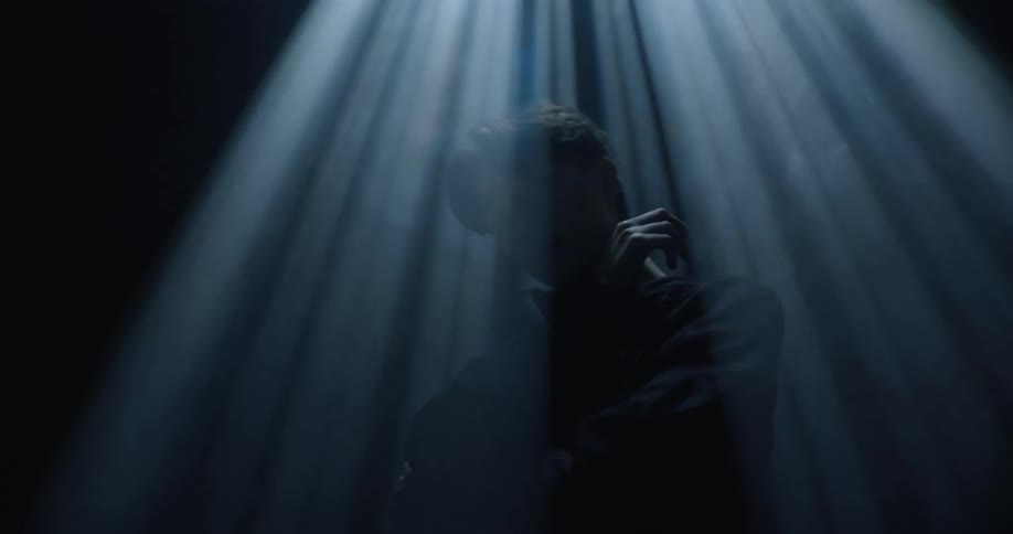A boy stands and poses while laser lights flash from above him