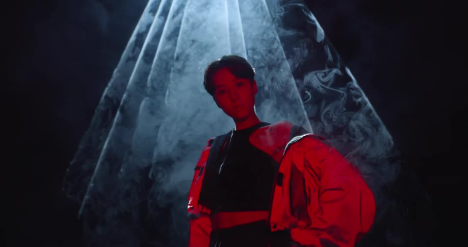 A woman is standing under the smoke filled light