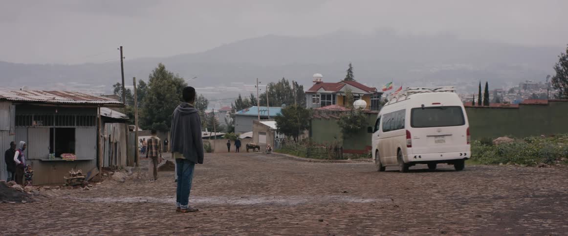 A man standing as a van passes by