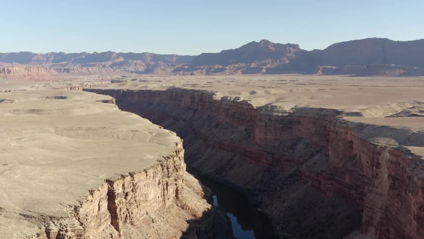 Canyon river gorge in desert with mountains on the horizon