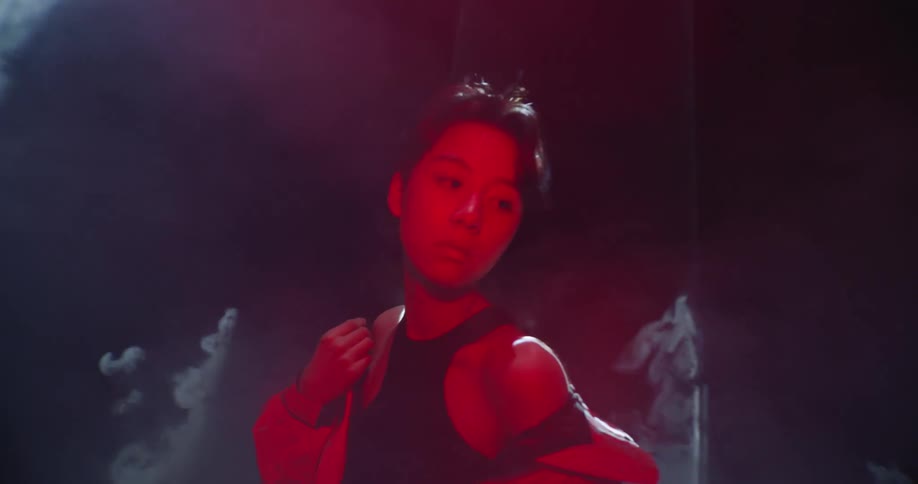 A young woman steps in to a spotlight which looks like smoke surrounding her