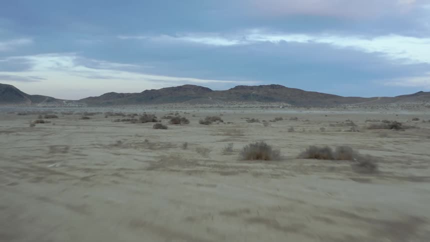 An arid flatland under a cloudy sky in evening
