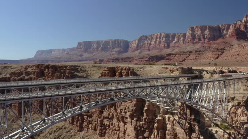 Bridge over canyon river with mountain mesa buttes nearby on a clear day