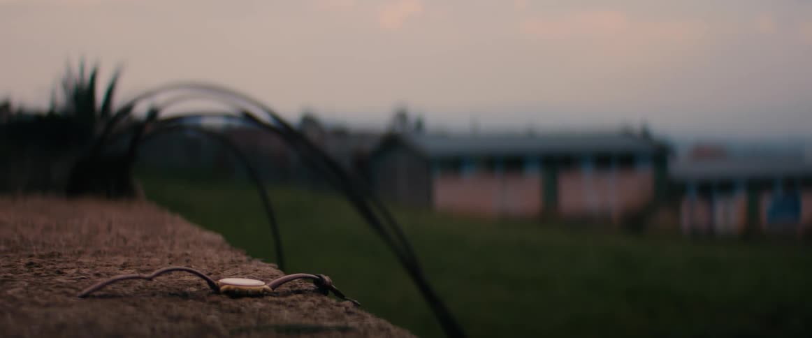 A wristwatch is left laying outdoors on a wall near a small building
