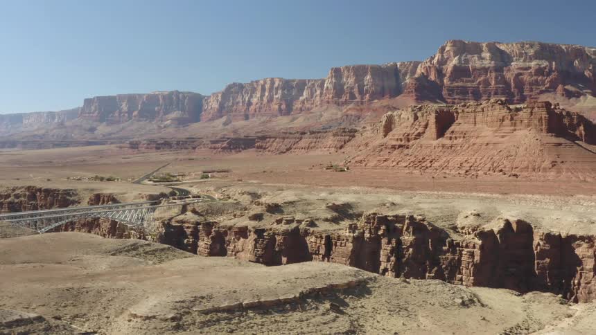Bridge over canyon gorge and mesa mountains on a clear day