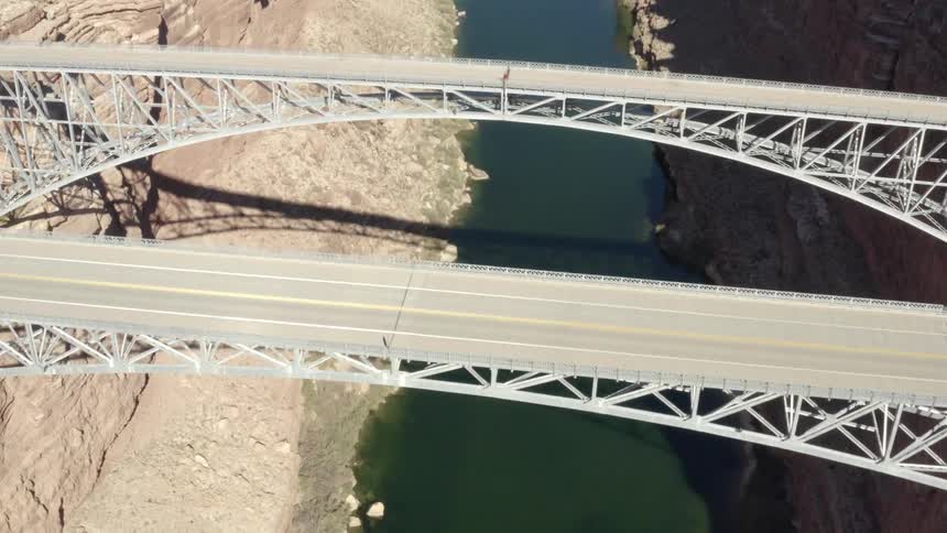 A pair of bridges span a canyon and the river at its bottom