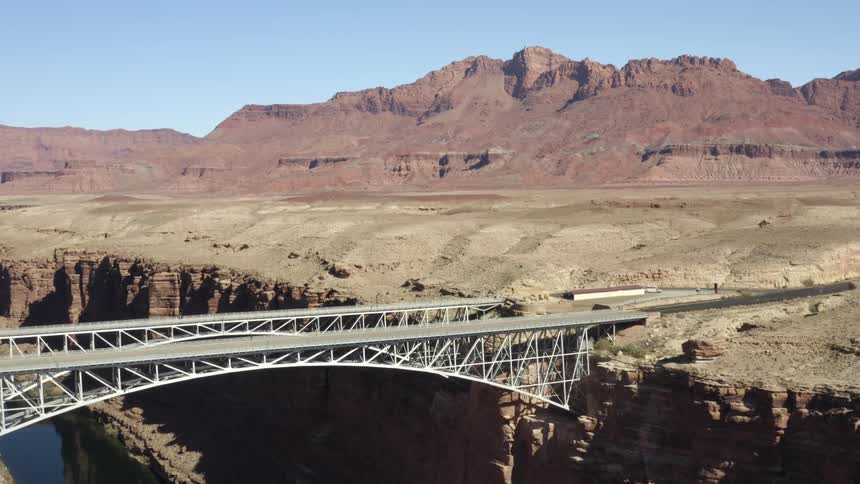 Bridge over river canyon and mountain mesa range on a clear day