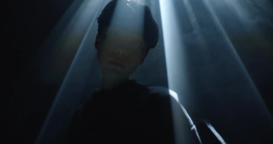 A woman is standing under the flickering lights