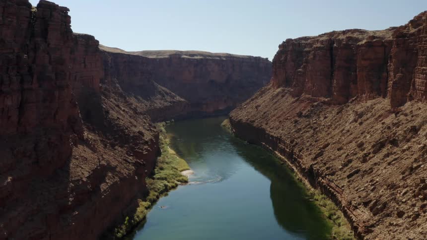 Canyon river gorge with bridge across canyon and mesa mountains on a clear day