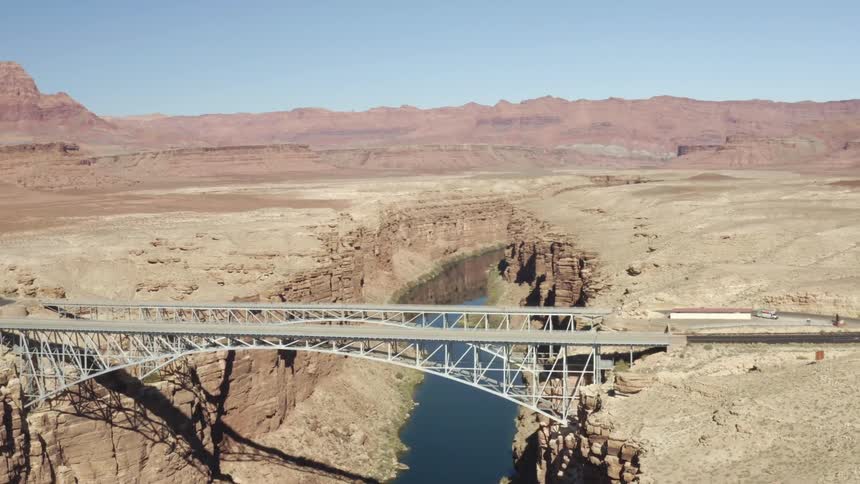 Aerial view of desert and mountains with a bridge over a river