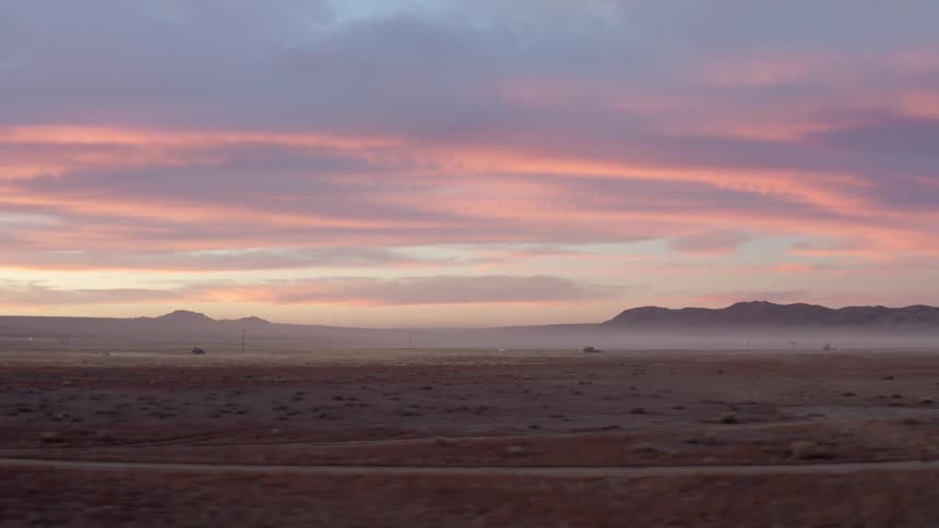 Colorful pink sky over rural area with mountains on the horizon