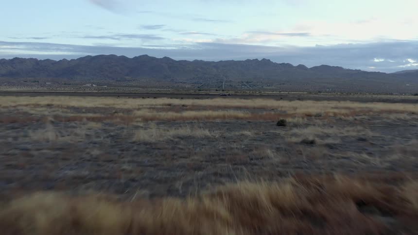Aerial view of the dry yellow grass on the plains near the mountains in the evening