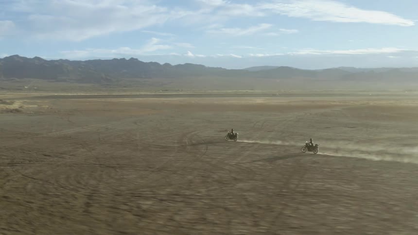 Aerial shot of two motorbikes driving across flat land
