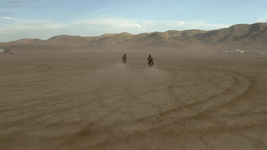 People ride bikes in dessert to large sand dunes