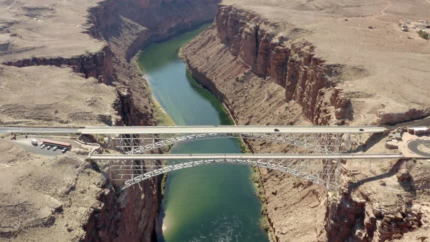Traffic travels across a bridge spanning a canyon containing a bluegreen river