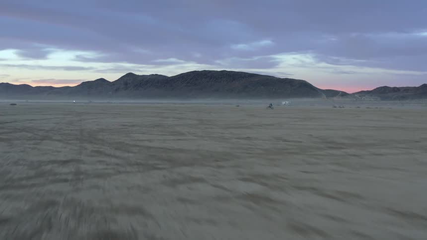 Aerial view of desert and mountains with cloudy pink and blue sky