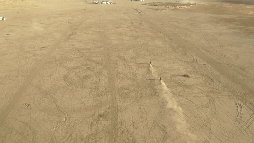 Two cyclists riding dirt bikes across the desert towards the mountains