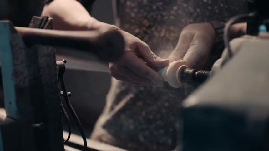 A person sands wood that is turning on a lathe