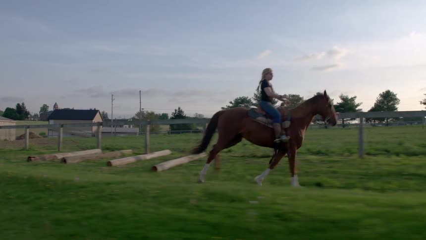 A woman is riding a horse on a farm
