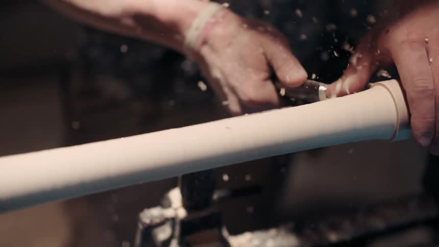 A person uses a tool to smooth a rod